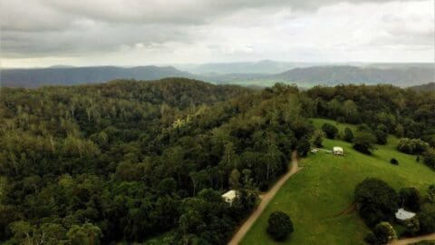 Birds-view on mystic, dark green mountains with a few white, little houses on the green pasture.