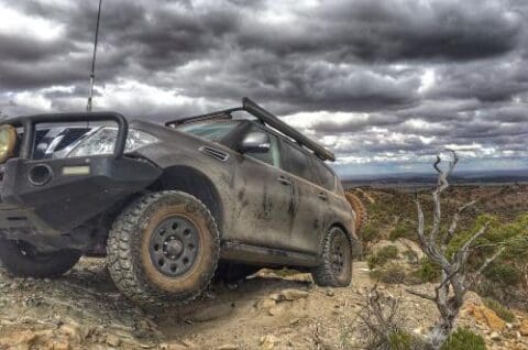 A rugged SUV with off-road modifications parked on a rocky terrain in the Bendleby Ranges under a cloudy sky.