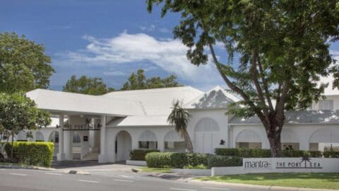 A one story white building with oval windows and a pointed roof.